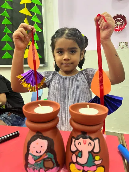 A student displays her hand-painted Diwali tea-light holders and festive hangings. Our Diwali workshops are all about creating beautiful decor to light up your home.