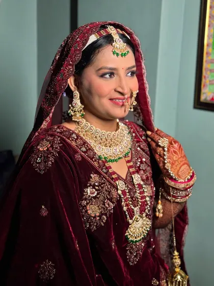 A stunning portrait of the bride in her deep maroon velvet outfit. The makeup is kept elegant and timeless to complement the richness of her attire.