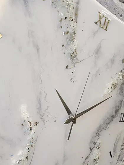 A timeless beauty dispatched to its new home. This 18 by 18 inch square clock features a white marble design with delicate crystal and gold details.