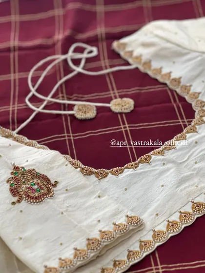 The back of the off-white blouse, showing the tie-up detail and a single motif.