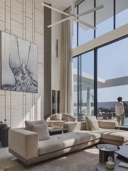 A closer look at the living area, where a large, abstract painting hangs on a textured marble wall. The comfortable, modern sofas and view of the pool make this the perfect space for both relaxation and entertaining.