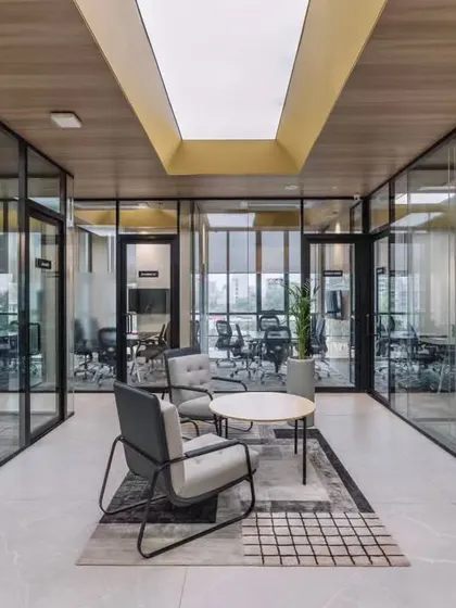This is a workspace designed for clarity and connection. The design uses glass partitions and open breakout areas to encourage collaboration, while a skylight and neutral tones create a bright, focused atmosphere for the team at RATNAAFIN.