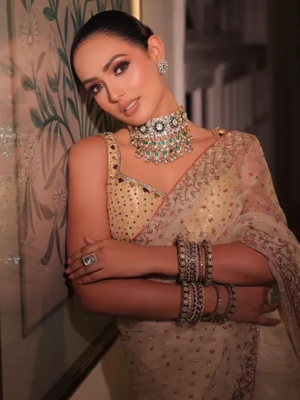 This seated pose highlights the heavy bangles and the intricate details of the choker.