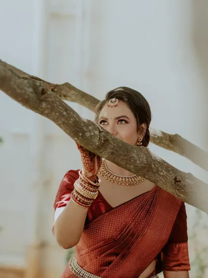 An artistic shot capturing the bride's beautiful eye makeup and traditional maang tikka. The focus is on her expressive eyes, enhanced with subtle shading and liner.