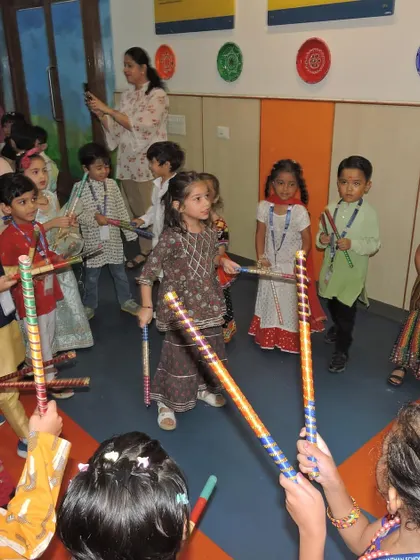 Children learn the steps of Dandiya, tapping their sticks together in a joyful and rhythmic dance.