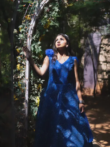 The play of light and shadow highlights the rich color and texture of this blue sequin gown in a beautiful garden setting.