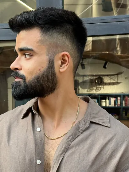 A great example of a modern men's haircut. This style features a sharp high-fade on the sides that cleanly transitions into a textured, voluminous top, paired with a perfectly groomed beard for a polished and contemporary look.