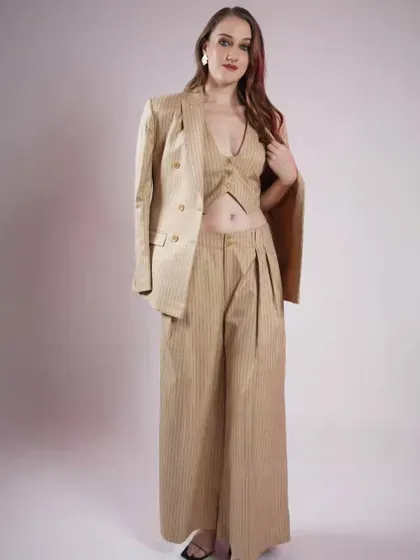A three-piece pinstripe suit in a neutral beige. The cropped waistcoat and wide-leg pants create a look that's both powerful and effortlessly cool.