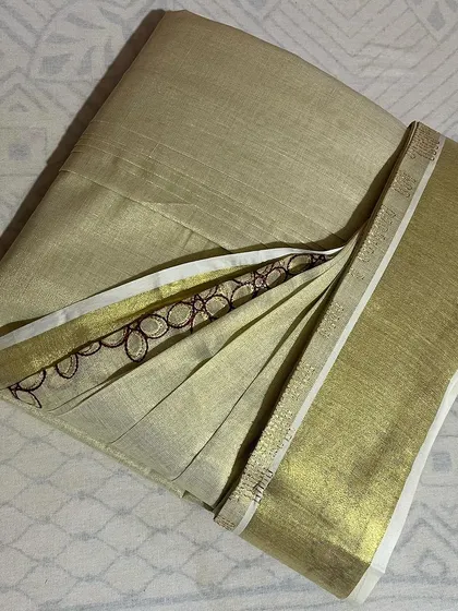 A lovely Kerala kasavu saree with a delicate embroidered border. I take special care with such fabrics to ensure the pleats are neat without damaging the material.