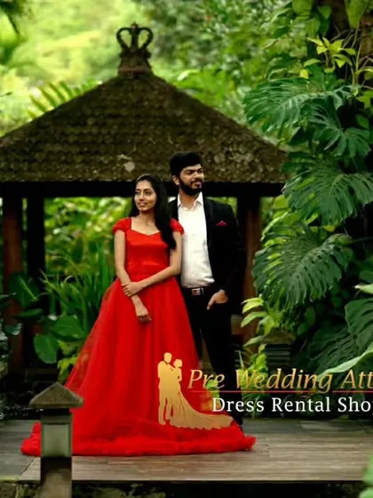A serene couple's portrait in a tropical garden. The red ruffled gown adds a vibrant pop of color against the lush greenery.