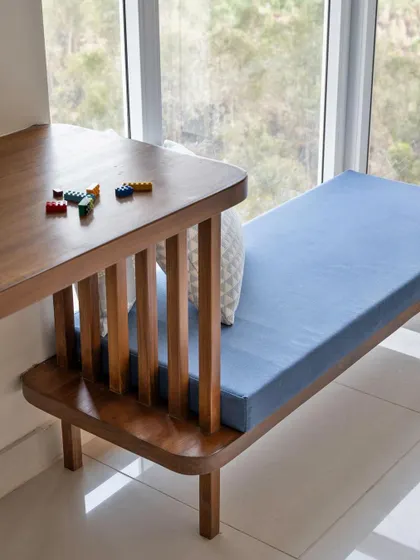 A detail of the custom study desk and window seat in the 'Utopian Dreams' kid's room. The wooden slats provide a visual connection between the two functional zones.