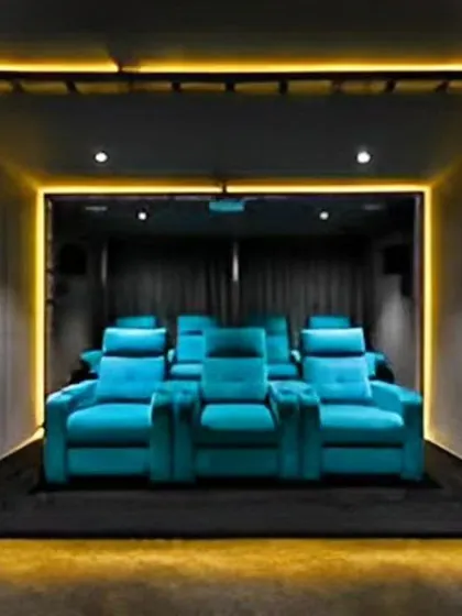 A dedicated home theater with plush recliner seats and ambient floor lighting. This design provides an immersive cinematic experience right at home.