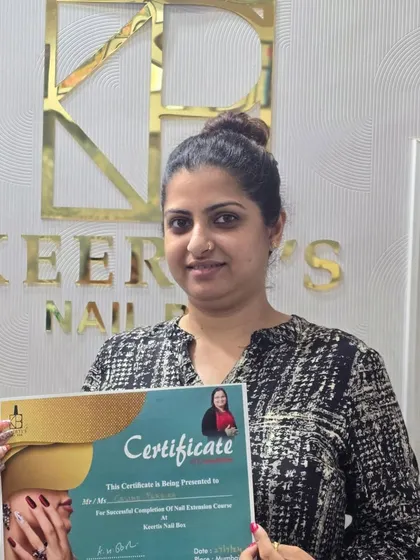 A graduating student proudly holding her certificate. This marks the beginning of a new chapter in her professional journey as a skilled nail technician.