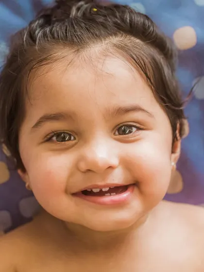 A heart-melting close-up of a smiling baby. This portrait captures the pure, unfiltered happiness of a child, with their bright eyes and joyful grin.