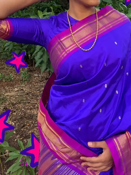 A close-up of a beautiful purple Paithani saree, with pink star doodles to make it sparkle.