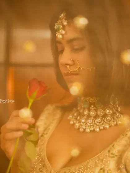 A dreamy and romantic bridal portrait. Using a soft focus and warm, glowing lights, this shot captures the bride in a quiet moment with a rose, creating a magical and ethereal feel.