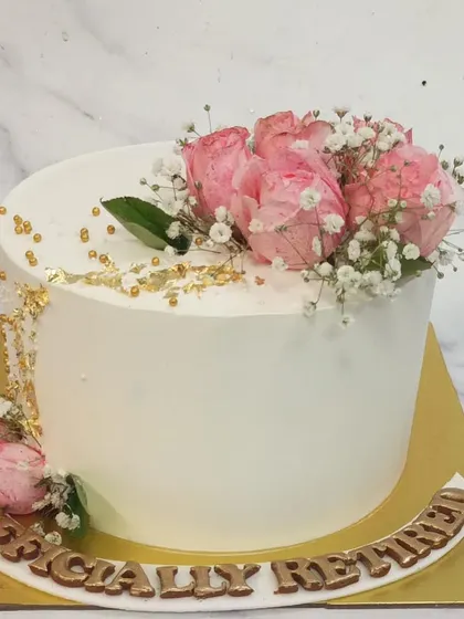 A beautiful cake to celebrate a special retirement. The clean white buttercream is adorned with fresh pink roses, baby's breath, and gold leaf accents for an elegant farewell.