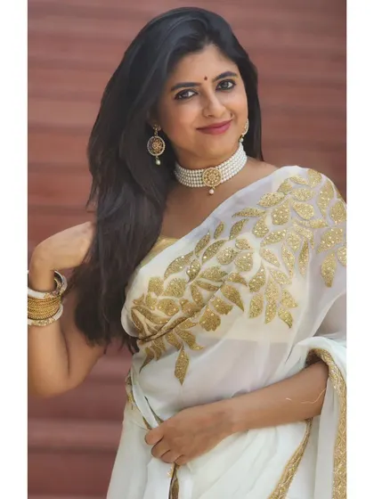An elegant white saree with gold embroidery, paired with a pearl choker. This look is sophisticated and perfect for upscale receptions or corporate ethnic day events.