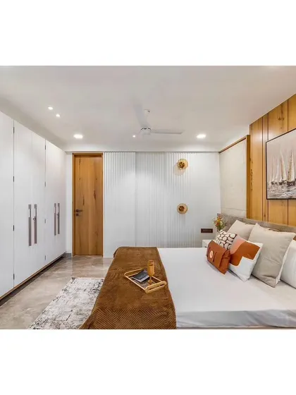 This bedroom combines natural wood paneling with clean white wardrobes for a look that is both warm and modern. The simple color palette and textures create a calm and restful environment.