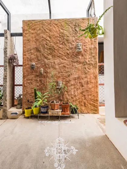 In the setback space of the Samvrruddhi home, we created a feature wall from textured mud plaster. This space, often overlooked, becomes a beautiful backdrop for plants and a welcoming rangoli.