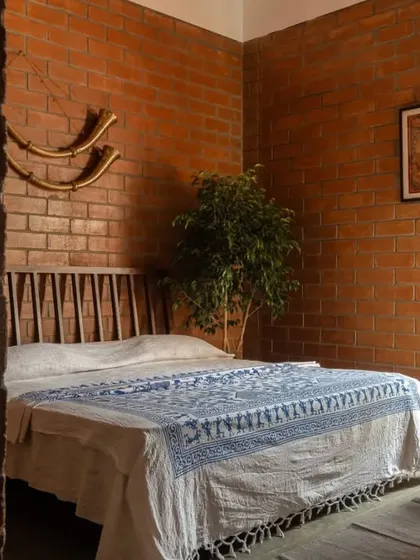 Designed for the grandmother of the house, this room is a cozy retreat with exposed brick walls, a custom wooden headboard, and a cool Kota stone floor.