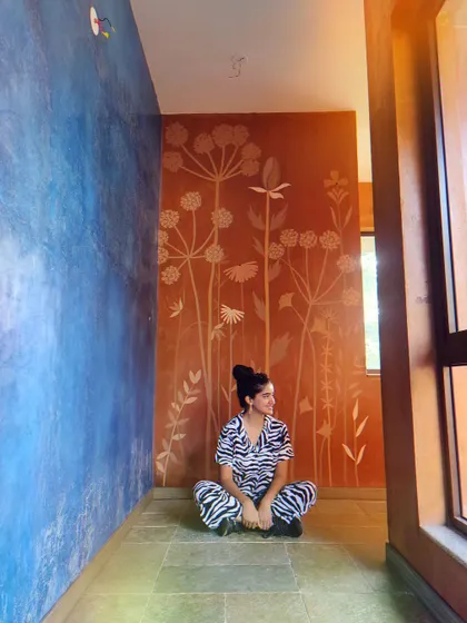 Taking a moment to appreciate the finished wildflower mural. The contrast between the earthy orange and the cool blue wall is stunning.