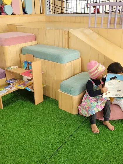 This reading nook is designed for comfort and quiet exploration. Here, two friends share a book, demonstrating how our environment naturally fosters social interaction and a shared love for reading.
