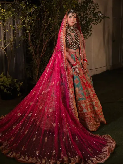 The drama of the trail. This shot showcases the incredible craftsmanship of her lehenga and the long, embellished veil, creating a truly royal bridal portrait.