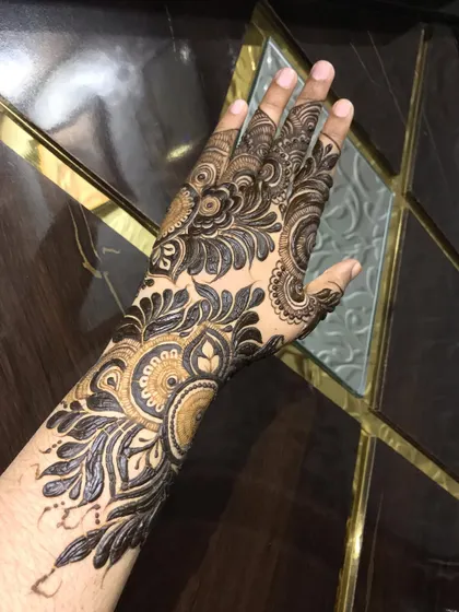 This design shows a beautiful blend of bold leaves and intricate, fine-line fillers. It's a semi-bridal style that covers the back of the hand and wrist with a rich, dense pattern.