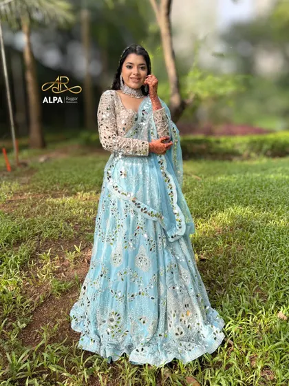 A perfect Sangeet look featuring a stunning mirror-work lehenga. The makeup is kept fresh and glowing, with a soft glam eye and a unique braided hairstyle to complement the entire outfit.