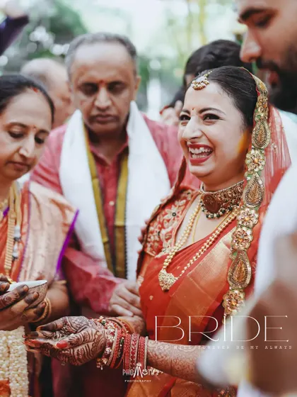 A radiant bride laughing during a wedding ritual, her happiness lighting up the frame.