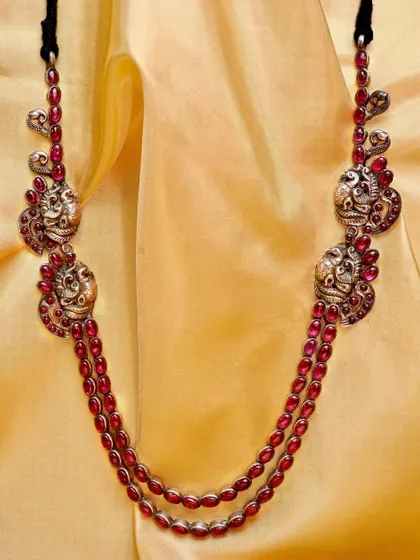 The red stone and silver peacock necklace, shown here against a different background to highlight its versatility.