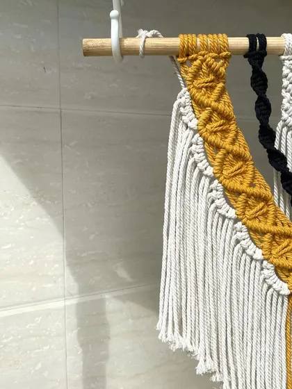 A detailed close-up of the diamond-patterned knotting on our yellow and black macrame wall hanging. This shows the precision and care we put into every single knot.