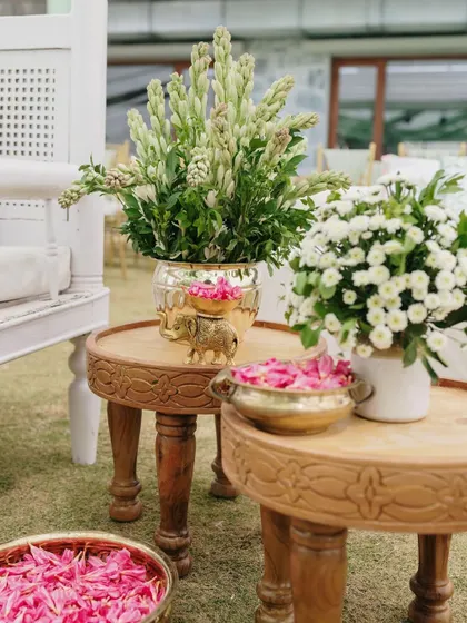 A close-up of the decor for the Bhaat ceremony, with bowls of pink flower petals and brass elements.
