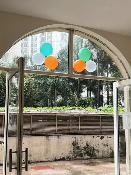 Tricolor balloon bunches placed on the arched windows of a clubhouse, a simple decoration for a corporate event.