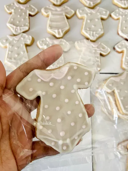 A close-up of a baby onesie iced cookie, showing the detailed piping work. These are perfect for baby shower favors.