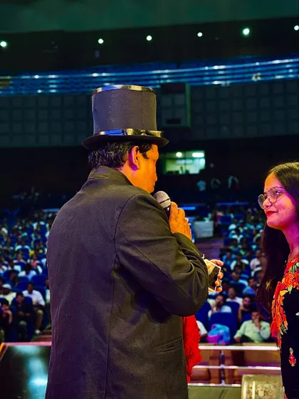 A close-up shot of me interacting with a volunteer on stage in a large auditorium. Even in a big venue, I make sure to create personal and engaging moments.