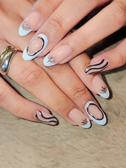 A modern and abstract design. This set combines a negative space look with light blue tips, chrome silver swirls, and 3D starburst accents for a unique, edgy style.
