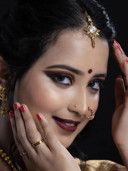 A close-up on the details. Notice the sharp winged eyeliner, the intricate nose ring (nath), and the flawless skin finish. Every detail is perfected to create a stunning bridal portrait.