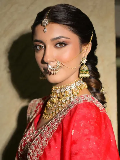 A confident and regal pose. The makeup is a perfect balance of soft glam and traditional elegance, ideal for a royal bridal look.