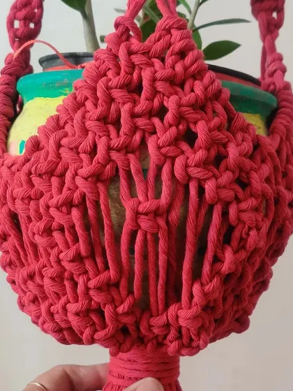 A new plant hanger design in a beautiful deep red, featuring a dense, textured basket.