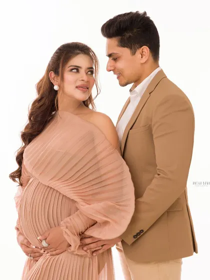 A look of love between an expecting couple. The unique pleated gown adds a touch of high fashion to this elegant maternity portrait.