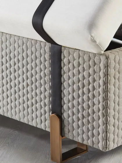 A close-up on the textured, quilted fabric and leather strap detail of the storage bench. This macro shot showcases the high-quality materials and unique design elements.