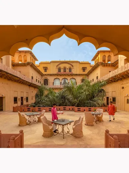 A view through a traditional archway into a sunlit courtyard. This composition uses architectural framing to draw the eye and convey the welcoming ambiance of the heritage hotel.