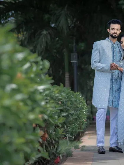 A classic couple portrait amidst lush greenery, showcasing their coordinated engagement outfits.