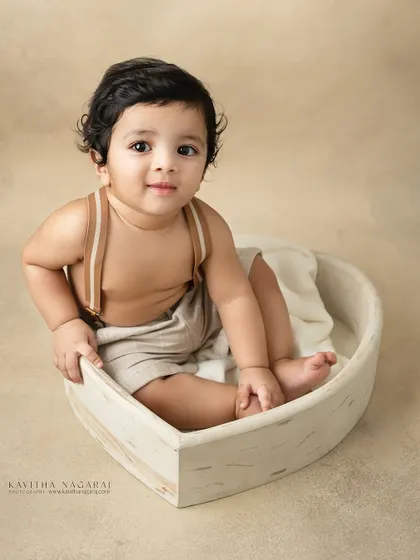 Ten-month-old twin brothers sitting in a heart-shaped basket. Their happy expressions and coordinated outfits make for an incredibly sweet portrait.
