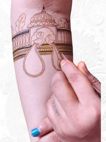 A live class demonstration of mehendi application on an arm. I guide my students through each step, showing them how to outline and fill intricate bridal elements.