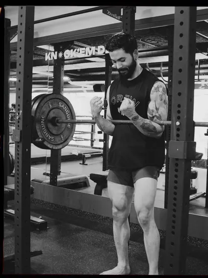 A member celebrates a good lift in the power rack. The black and white film style captures the raw, focused energy of our training floor.