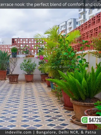 A view of a terrace I designed, featuring patterned tile flooring and a variety of potted plants. The terracotta brick jali wall adds a rustic and traditional touch while ensuring privacy.