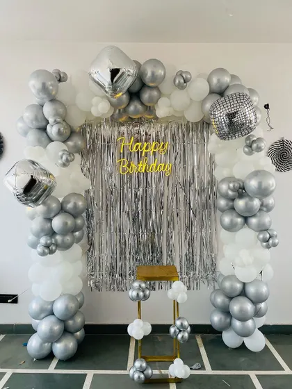 An elegant and affordable alternative to a full shimmer wall, this backdrop uses a silver fringe curtain to create a sparkling effect. The silver and white balloon arch with diamond and disco ball foil balloons completes this chic birthday decoration.